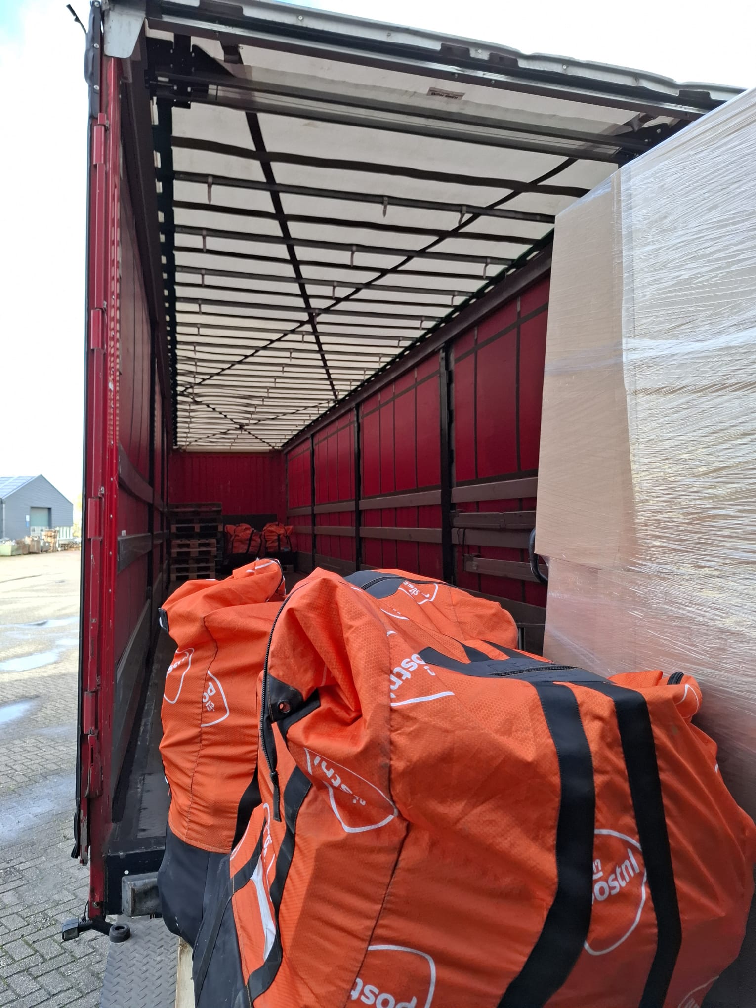 Oranje PostNL zakken uitgeladen uit een vrachtwagen voor SecretBoxes